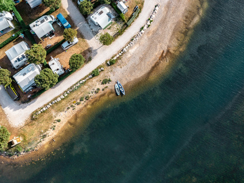 Vista aerea del Camping Orsera in Istria, Croazia, con camper e barche lungo la riva del mare.