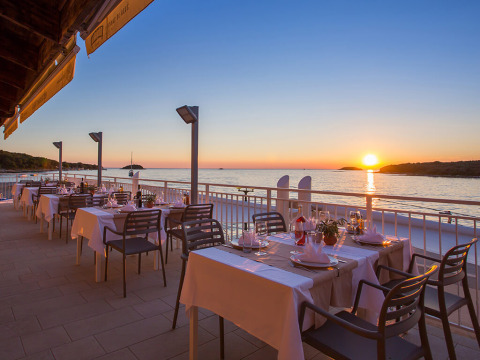 Ristorante all'aperto al Camping Orsera in Istria, Croazia, con vista mare e tramonto suggestivo.
