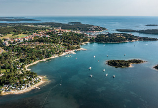 Aerial view of Camping Orsera holiday park in Istria, Croatia, showing coastline, boats, and lush green areas.