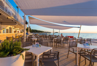 Zona pranzo all'aperto al Camping Orsera in Istria, Croazia, con vista mare e arredi moderni.