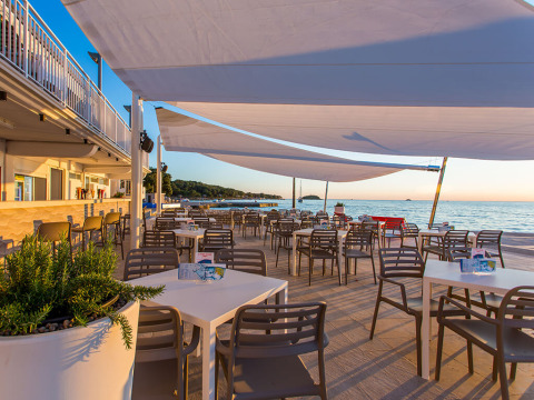 Buitenterras van Camping Orsera in Istrië, Kroatië, met uitzicht op zee en moderne zitplaatsen.