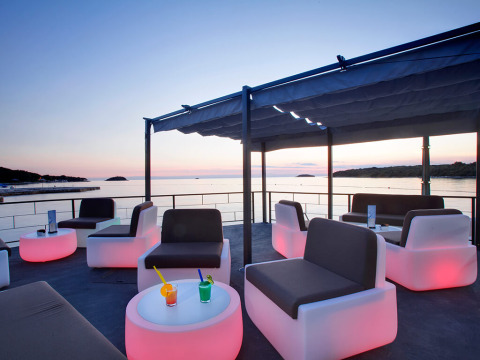 Modernes Lounge-Areal mit stylischen Sitzgelegenheiten und Meeresblick bei Sonnenuntergang im Camping Orsera.