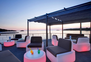 Espace lounge extérieur moderne avec vue sur la mer au coucher du soleil au Camping Orsera, Istrie, Croatie.