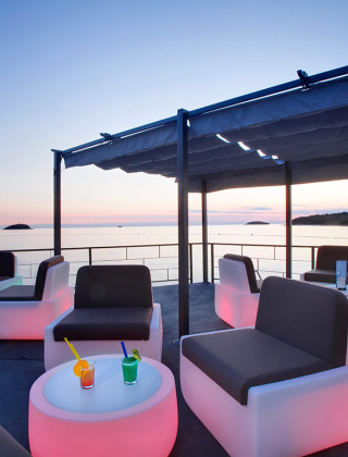 Buitenlounge met moderne zitplaatsen en uitzicht op zee bij zonsondergang bij Camping Orsera in Istrië, Kroatië.