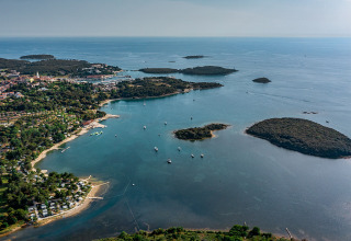 Veduta aerea di Camping Orsera sulla costa istriana, Croazia, con isole e barche nel mare azzurro.