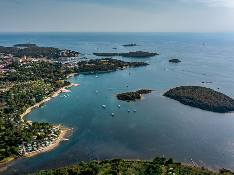 Veduta aerea di Camping Orsera sulla costa istriana, Croazia, con isole e barche nel mare azzurro.