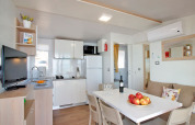 Moderne glamping-verblijfplaats met keuken, eettafel, zetel en warme, uitnodigende inrichting.