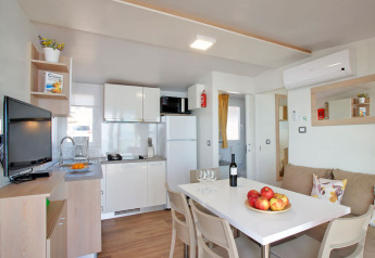 Alloggio glamping moderno con cucina, tavolo da pranzo, divano e ambiente luminoso e accogliente.
