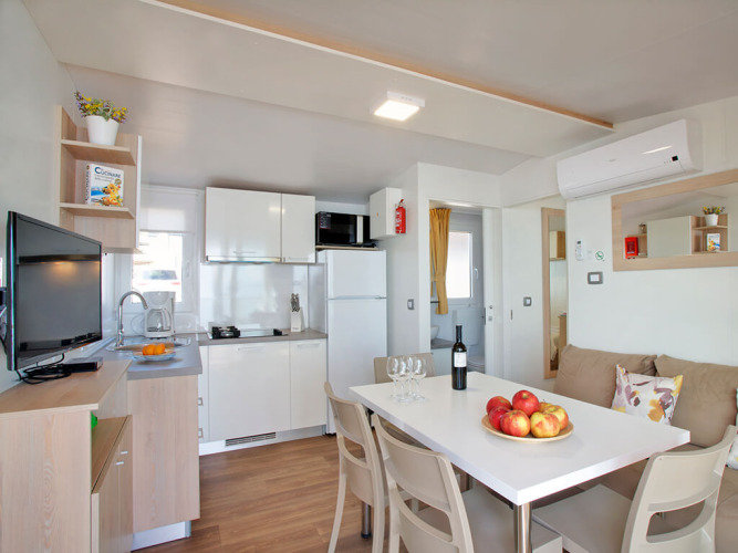 Moderne glamping-accommodatie met keuken, eettafel, bank en lichte, gezellige inrichting.