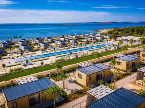 Camping Arena Grand Kažela in Istria, Croatia, featuring modern cabins, a long pool, and a scenic sea view.