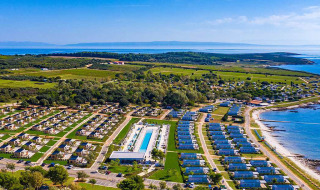 Luftfoto af Camping Arena Grand Kažela-feriepark med hytter, pool og udsigt over kysten i Istrien, Kroatien.