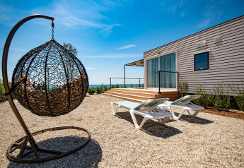 Udendørs område ved Camping Villa chalet med hængestol, solsenge, træterrasse og havudsigt.