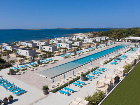 Vista aerea del Camping Arena Grand Kažela in Istria, Croazia, con piscina, lettini e vista mare.
