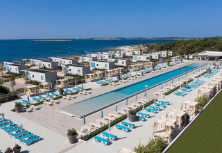 Vista aerea del Camping Arena Grand Kažela in Istria, Croazia, con piscina, lettini e vista mare.