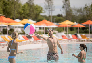 Family playing with a colorful beach ball in the pool at Camping Arena Grand Kažela, Istria, Croatia.