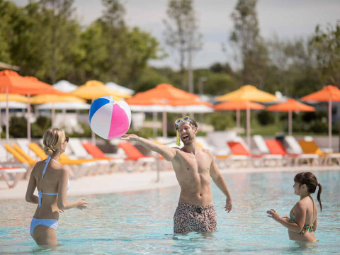 Famiglia che gioca con un pallone colorato in piscina al Camping Arena Grand Kažela, Istria, Croazia.