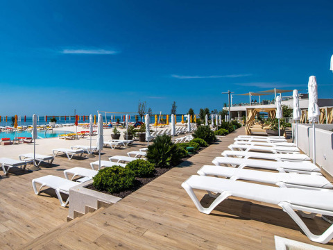 Zonneterras met ligbedden en parasols aan het zwembad bij Camping Arena Grand Kažela in Istrië, Kroatië.