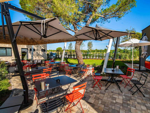 Outdoor dining area with colorful chairs and umbrellas at Camping Arena Grand Kažela, Istria, Croatia.