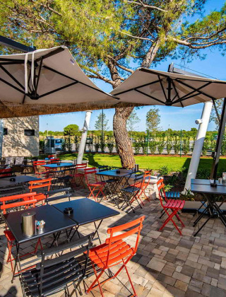 Udendørs spiseområde med farverige stole og parasoller på Camping Arena Grand Kažela, Istrien, Kroatien.