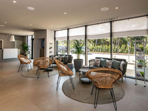 Spacious and modern lobby with rattan chairs, couches, and large windows at Camping Arena Grand Kažela.
