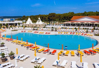 Outdoor swimming pool with colorful sunbeds and umbrellas at Camping Arena Grand Kažela, Istria, Croatia.