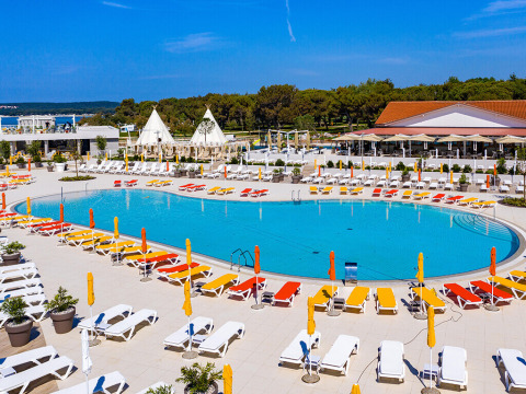 Piscina all'aperto con lettini colorati e ombrelloni al Camping Arena Grand Kažela, Istria, Croazia.