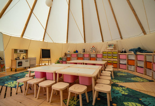 Area bimbi in una tenda tipi con sedie colorate, tavoli e giochi a Grand Kažela, Croazia.