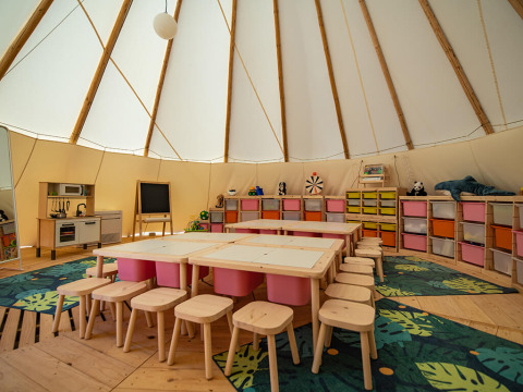 Espace enfants dans un tipi avec chaises, tables et rangements colorés au Grand Kažela, Croatie.