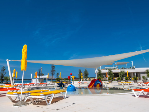 Tumbonas soleadas y zona de juegos acuáticos infantiles en Camping Arena Grand Kažela, Istria, Croacia.