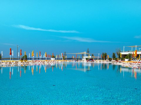 Large swimming pool with sun loungers and colorful umbrellas at Camping Arena Grand Kažela in Istria, Croatia.