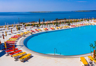 Ampia area piscina al Camping Arena Grand Kažela in Istria, Croazia, con vista mare e lettini.