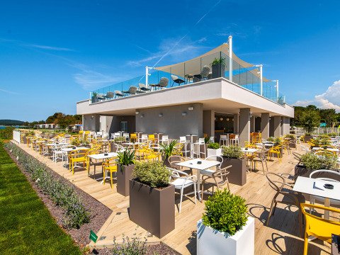 Zona pranzo all'aperto al Camping Arena Grand Kažela in Istria, Croazia, con sedie colorate e tanti vasi.