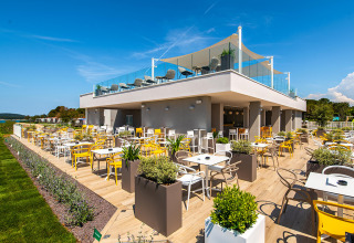 Outdoor dining terrace at Camping Arena Grand Kažela in Istria, Croatia, featuring bright chairs and planters.