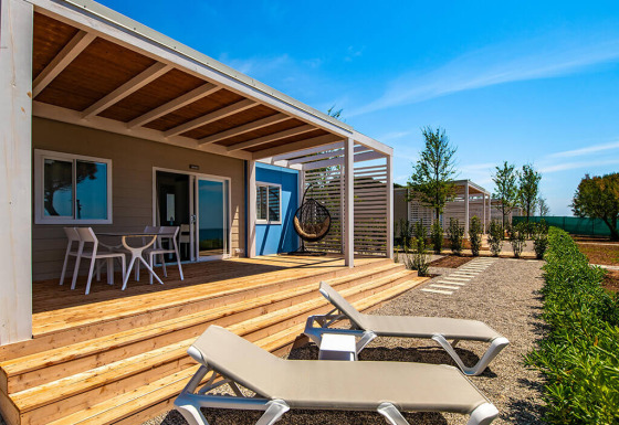 Terrasse eines Camping Home Next Chalets mit Sonnenliegen, Essbereich und moderner Überdachung.