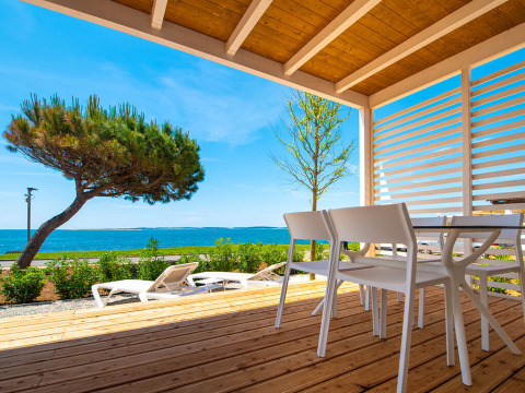 Vista dalla terrazza in legno di Camping Home Next, Camping Arena Grand Kažela, Croazia, sul mare e sdraio.