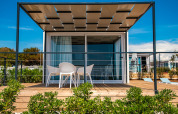 Chalet moderne avec terrasse et mobilier de jardin au Camping Arena Grand Kažela en Croatie sous un ciel bleu.