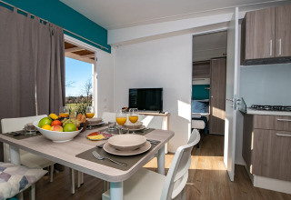 Essbereich für vier Personen in modernem Chalet mit Obstschale, Saft und Blick ins Schlafzimmer.