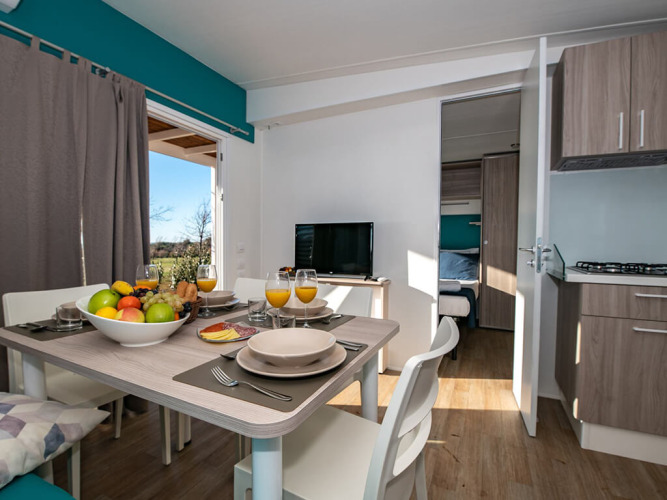 Mesa de comedor para cuatro en cocina de chalet moderno, con fruta, zumo y vista al dormitorio.