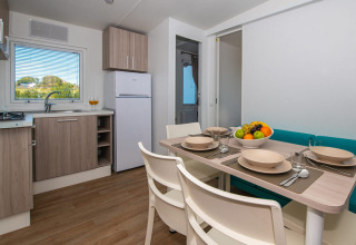 Modernes Chalet mit Küche, Esstisch für vier Personen, Obstschale und Blick auf die Natur draußen.