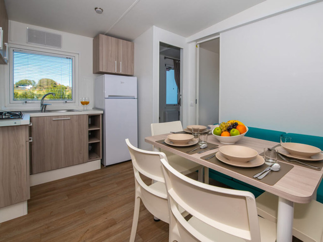 Cucina chalet moderna con zona pranzo apparecchiata per quattro, fruttiera e finestra con vista verde.