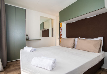 Moderne soveværelse i Camping Home Green på Camping Arena Grand Kažela i Kroatien med dobbeltseng.