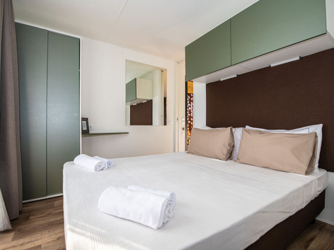 Moderne soveværelse i Camping Home Green på Camping Arena Grand Kažela i Kroatien med dobbeltseng.