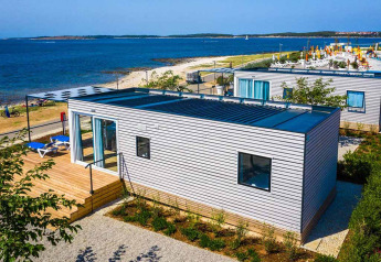 Chalet Camping Villa First Row ved havet, med moderne træfacade, terrasse og liggestole på stranden.