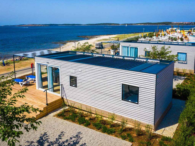 Chalet Camping Villa First Row aan het water, moderne houten chalet met terras en zicht op het strand.