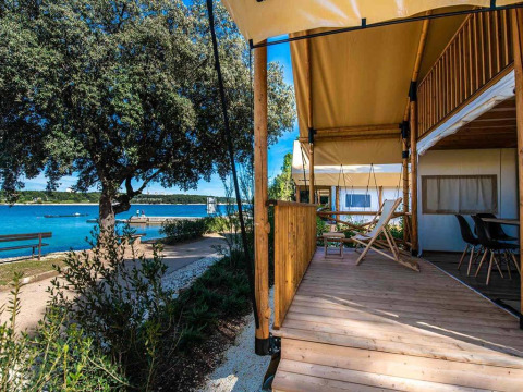 Tenda safari glamping con due camere e terrazza in legno, vista acqua, a Camping Arena Stoja, Croazia.