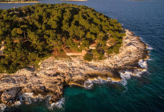 Aerial view of Camping Arena Stoja in Istria, Croatia, showing a forested shoreline and clear blue sea.