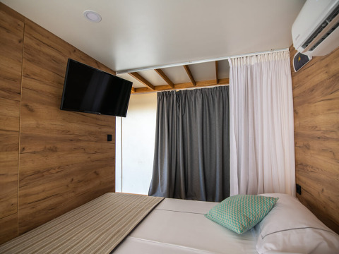 Interieur van een glamping safari tent met houten wanden, TV en bed op Camping Arena Stoja, Kroatië.
