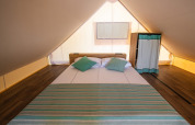 Vista interna di una tenda safari loft con letto matrimoniale e armadio al Camping Arena Stoja in Croazia.