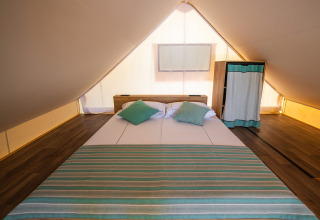 Binnenzicht van een glamping safari loft tent met tweepersoonsbed en kast op Camping Arena Stoja Kroatië.