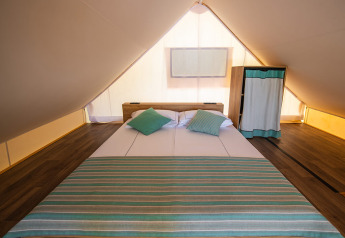 Interior view of safari loft tent with double bed and wardrobe at Camping Arena Stoja in Croatia.